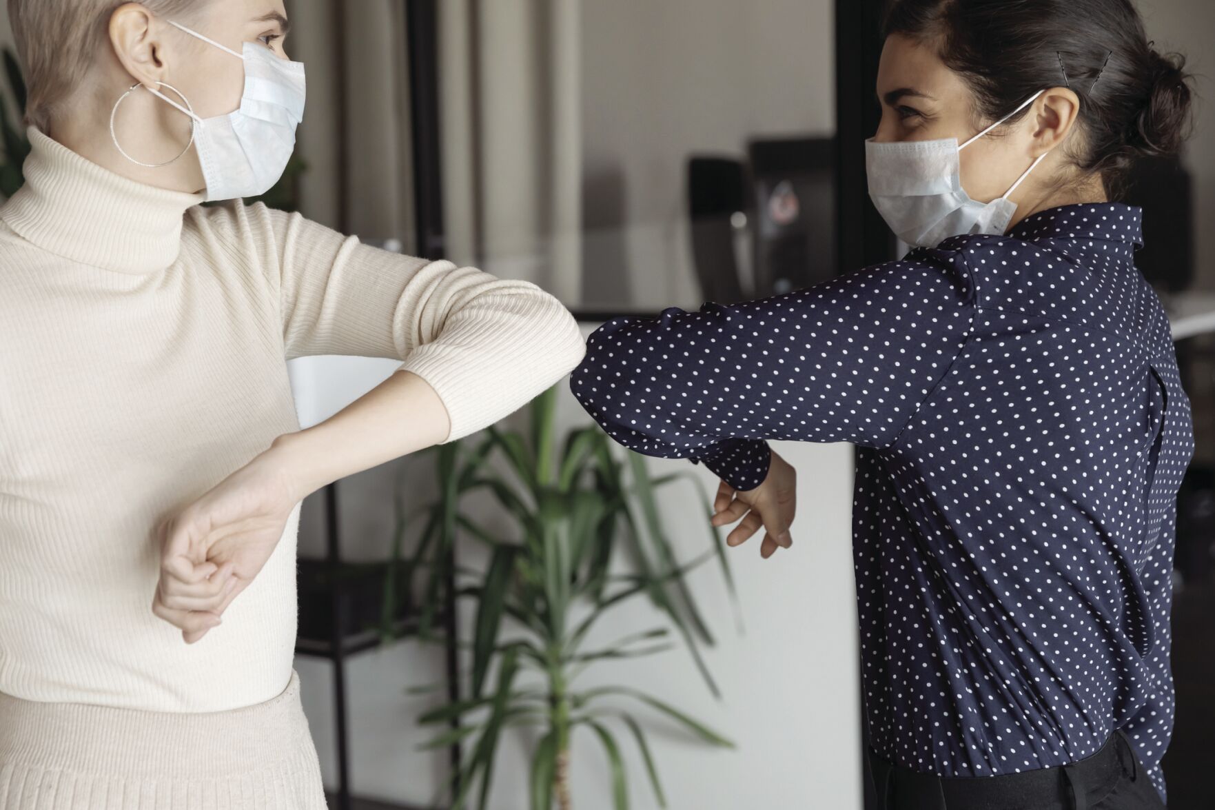 female colleagues greeting each other by bumping elbows gesture